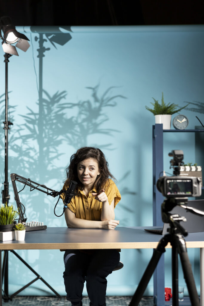 Jolly woman filming vlog pointing finger to high tech camera